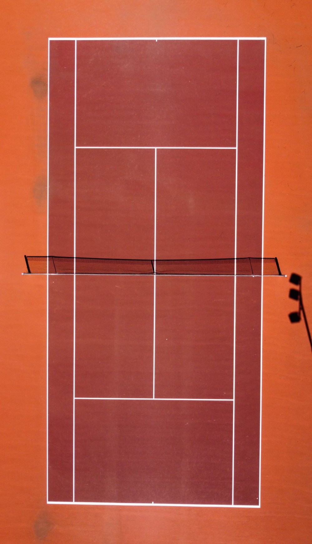 Aerial view of a clay tennis court with net